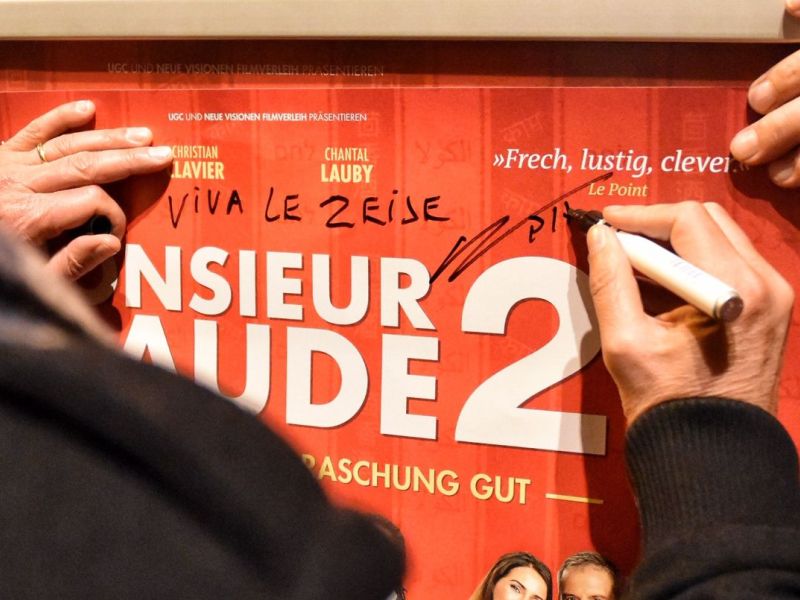 Regisseur Philippe de Chauveron signiert das Filmposter.